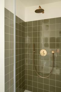 梅拉诺奥特曼古特套房及早餐酒店的绿色瓷砖浴室内带软管的淋浴