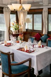 下龙湾传奇下龙私人邮轮酒店 - 哈亚巡游管理局的一张桌子、白色的桌布、椅子和窗户