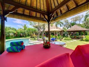 坎古Villa Kakatua的一个带红色桌子和游泳池的户外用餐区