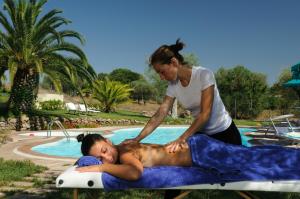 阿尔盖罗Alghero Resort Country Hotel & Spa的帮助男人在游泳池边躺在木筏上的女人