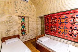 布哈拉Ohun Caravansarai 16 th century的一间设有两张床的客房,墙上挂着一幅画