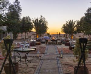 梅尔祖卡Merzouga Stars Luxury Camp的庭院配有桌椅和壁炉
