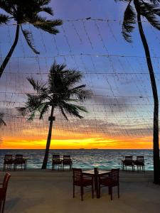 迪弗西Heron Beach Hotel - The Best Maldivian Getaway in Dhiffushi,Maldives的海滩上的桌椅和日落