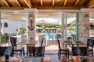 古维亚Marietta's Resort by Konnect, Gouvia Corfu的一间带桌椅的餐厅和一个游泳池