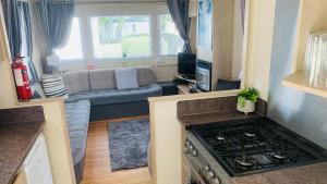 特维德上游的贝里克WL56 - Amazing Cosy Three Bedroom Mobile Home with DECKING Haggerston CASTLE Holiday Park - ENTERTAINMENT PASSES NOT INCLUDED!的带沙发和炉灶的小客厅