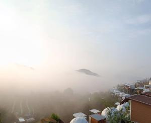 清迈Phutonso Homestay的一座带房屋的雾 ⁇ 城市和一座山的背景