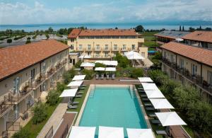 拉齐塞Leonardo Hotel Lago di Garda - Wellness and Spa的享有带游泳池和遮阳伞的度假村的空中景致
