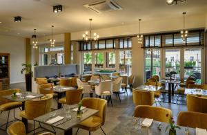 拉齐塞Leonardo Hotel Lago di Garda - Wellness and Spa的餐厅设有桌椅和窗户。