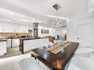 开普敦Urban Style House with Jacuzzi & Garage的厨房以及带木桌和白色椅子的用餐室。