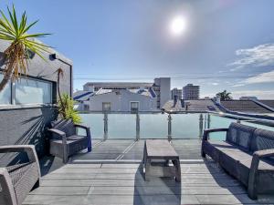 开普敦Urban Style House with Jacuzzi & Garage的阳台的天井设有2张长椅和1张桌子