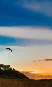 卡诺格布拉达Raio de Sol Residence的日落时在海滩上放风筝的人