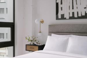 长岛市Sonder Court Square的卧室配有白色的床和带西德西德西德床的床头柜。