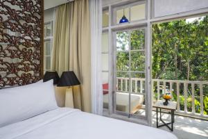 沙努尔萨伽拉田园酒店的一间卧室配有一张床,阳台设有窗户