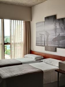 纳塔尔9006 Suites Natal Hotel的一间卧室设有两张床和一个带冲浪板的窗户。