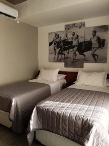 纳塔尔9006 Suites Natal Hotel的一间卧室设有两张床,墙上挂着一幅画