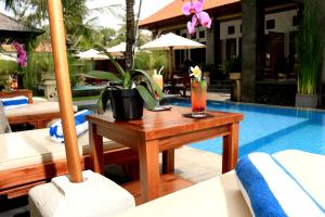 努沙杜瓦Kubu Garden Suites & Villas Nusa Dua的池畔桌子和饮料