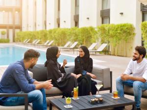 吉达Mövenpick Hotel Tahlia Jeddah的一群人坐在游泳池前