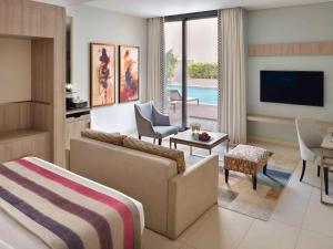 吉达Mövenpick Hotel Tahlia Jeddah的客厅配有床、电视和沙发。