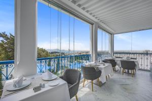 西迪·布·赛义德La Menara Hotel & SPA的餐厅设有白色的桌椅和大窗户。