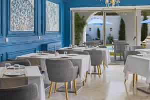 西迪·布·赛义德La Menara Hotel & SPA的餐厅设有白色的桌椅和蓝色的墙壁
