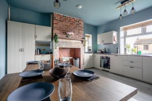 Clayton WestHolmfield House的厨房配有木桌和壁炉。