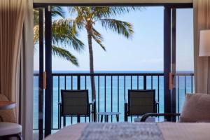拉海纳OUTRIGGER Kāʻanapali Beach Resort的阳台享有两把椅子和一棵棕榈树的景致。