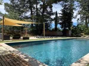 普罗旺斯艾克斯Superbe annAix de villa的一个带黄色遮阳伞和长椅的游泳池