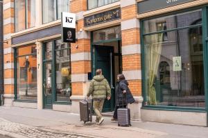 奥斯陆K7 Hotel Oslo的两个人带着行李走在街上
