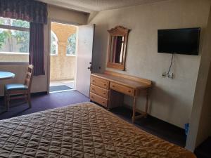 提华纳扎哈格扎别墅酒店的一间卧室配有一张床、一张书桌和一台电视