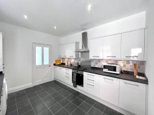 盖茨黑德2 Bedroom, Spacious, Close To Newcastle&gateshead的白色的厨房配有白色的橱柜和微波炉