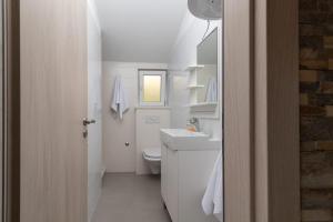 特罗吉尔Apartmani Grga的白色的浴室设有水槽和卫生间。