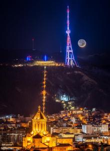 第比利斯Marmenio Hotel - Tbilisi的享有夜间城市美景,设有塔楼