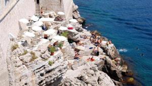 杜布罗夫尼克Ella la Bella III Dubrovnik Old town的一群人坐在靠近水面的悬崖上