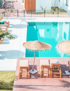 Parque HolandesShambhala Fuerteventura的游泳池旁的游泳池配有两把椅子和一把遮阳伞