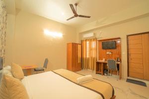 德拉敦Hotel Rudra的一间卧室配有一张带吊扇的床和一张书桌。