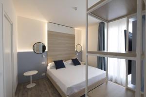 里米尼拜亚酒店的一间卧室配有双层床和书桌