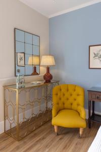 米克诺斯城科嫩尼公寓的一张黄色椅子,放在带桌子和镜子的房间