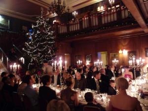 阿利士皇家天地酒店的一群人坐在桌子上,坐在一个有圣诞树的房间