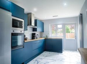 贝克斯利黑思Royal Luxe 6 Bed House in London的蓝色的厨房,配有蓝色的橱柜和窗户