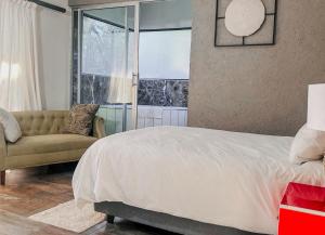 内尔斯普雷特View Inn Exclusive Lodge的一间卧室配有一张床、一张沙发和一个窗口