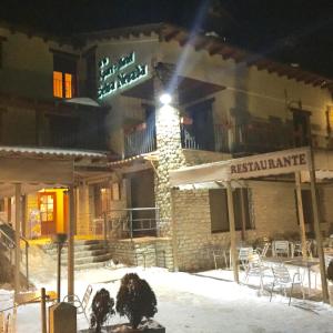 La Virgen de la VegaApart-Hotel Selva Nevada的雪地里餐厅标志的建筑物