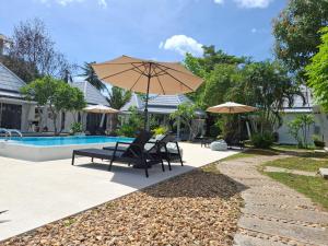 苏梅岛Thiptara Resort的一个带两把椅子和一把遮阳伞的庭院,毗邻一个游泳池