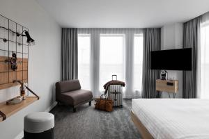 圣艾修伯里Moxy Lyon Airport的酒店客房配有一张床、一把椅子和一台电视。