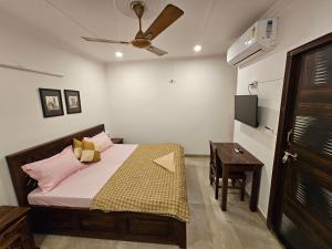 新德里Gautam Nagar Homestay South Delhi的一间卧室配有一张床、一张桌子和吊扇