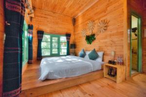 Kon Von KlaMăng Đen Treehouse Village Resort & Zipline的木制客房内的一间卧室,配有一张床