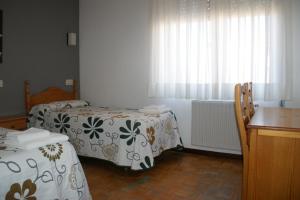 纳瓦莱诺Hostal La Tablada的客房设有两张床、一张桌子和一个窗户。