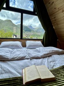 卡兹贝吉Hillside Kazbegi的一张床上的窗户,上面有一本书