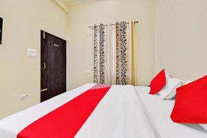 斋浦尔Hotel Arn Plaza的卧室配有带红色枕头的大型白色床