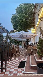 马格德堡Hotel Deutsches Haus Restaurant Olympia的一个带桌椅和遮阳伞的庭院