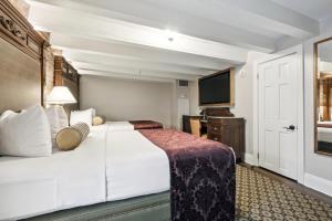 新奥尔良法国市场旅馆的酒店客房设有白色的床和电视。